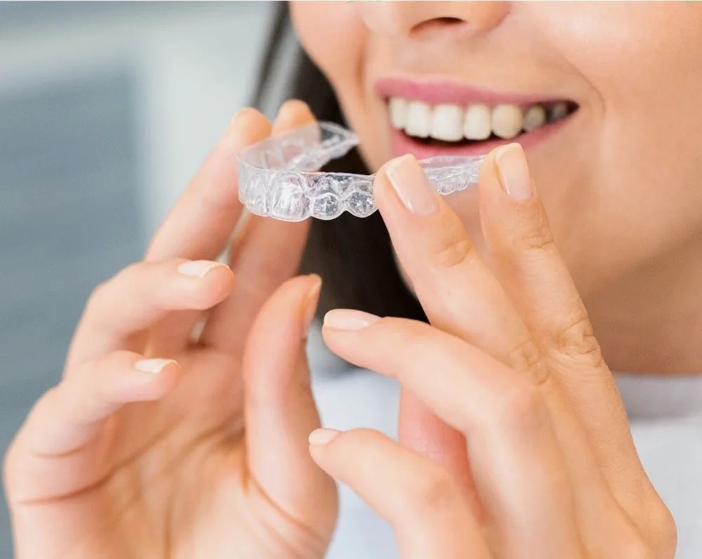 Smiling woman placing a clear aligner tray